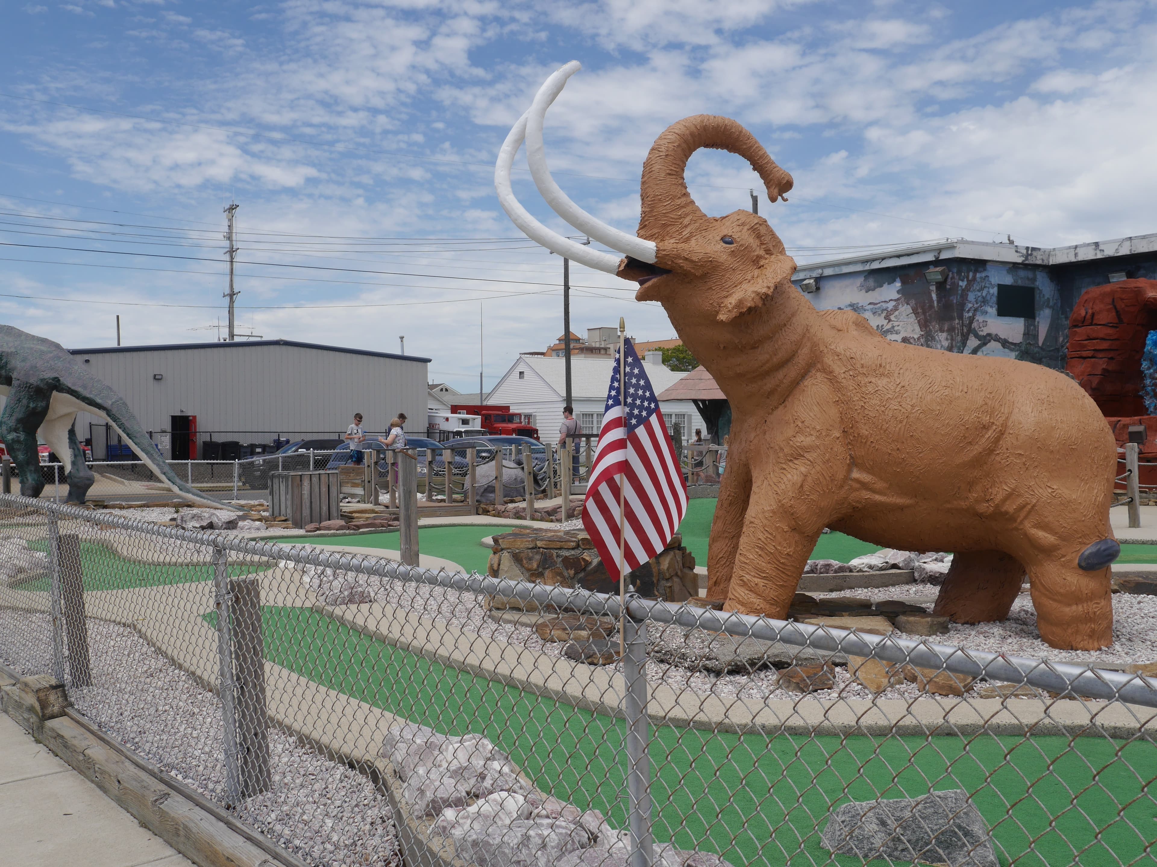 Mammoth statue at Jurassic Mini Golf with American flag